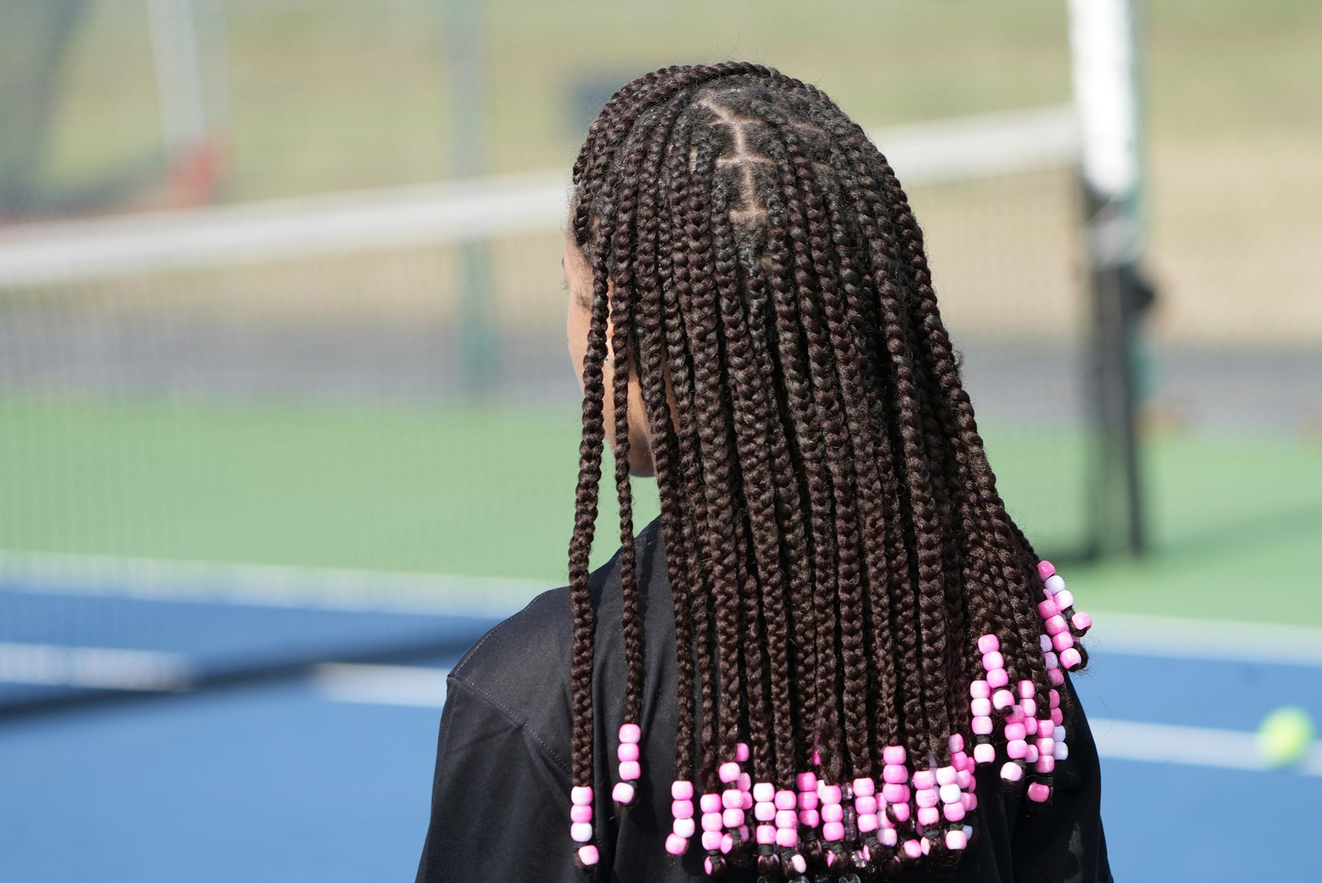 a woman with long box braids on a tennis court